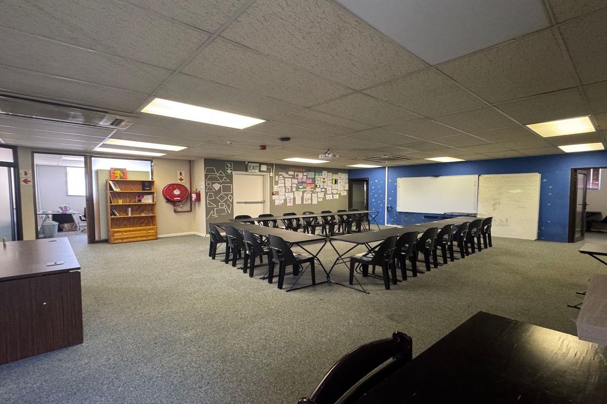 Spacious commercial office or training room featuring carpeted flooring, suspended ceilings, integrated lighting, and wall-mounted whiteboards, suitable for professional meetings or educational use.
