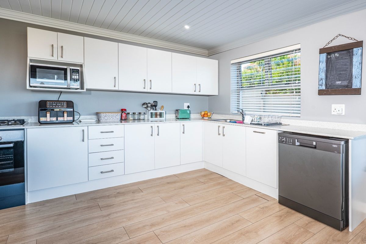 Modern kitchen featuring white cabinetry, stone-look countertops, integrated oven, and wood-look flooring, offering a clean and functional workspace.