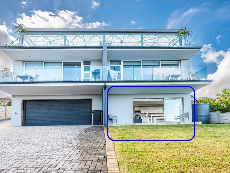 Modern apartment exterior featuring a paved driveway, integrated garage, and a ground-level patio area with direct access to the open-plan living space.
