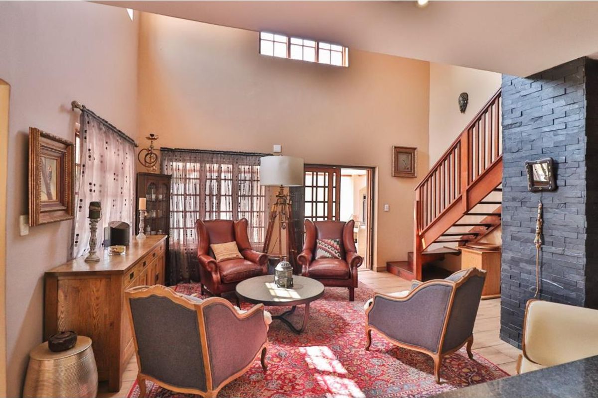 Spacious double-volume living area featuring a striking black stone feature wall, wooden staircase, and large windows allowing for abundant natural light.