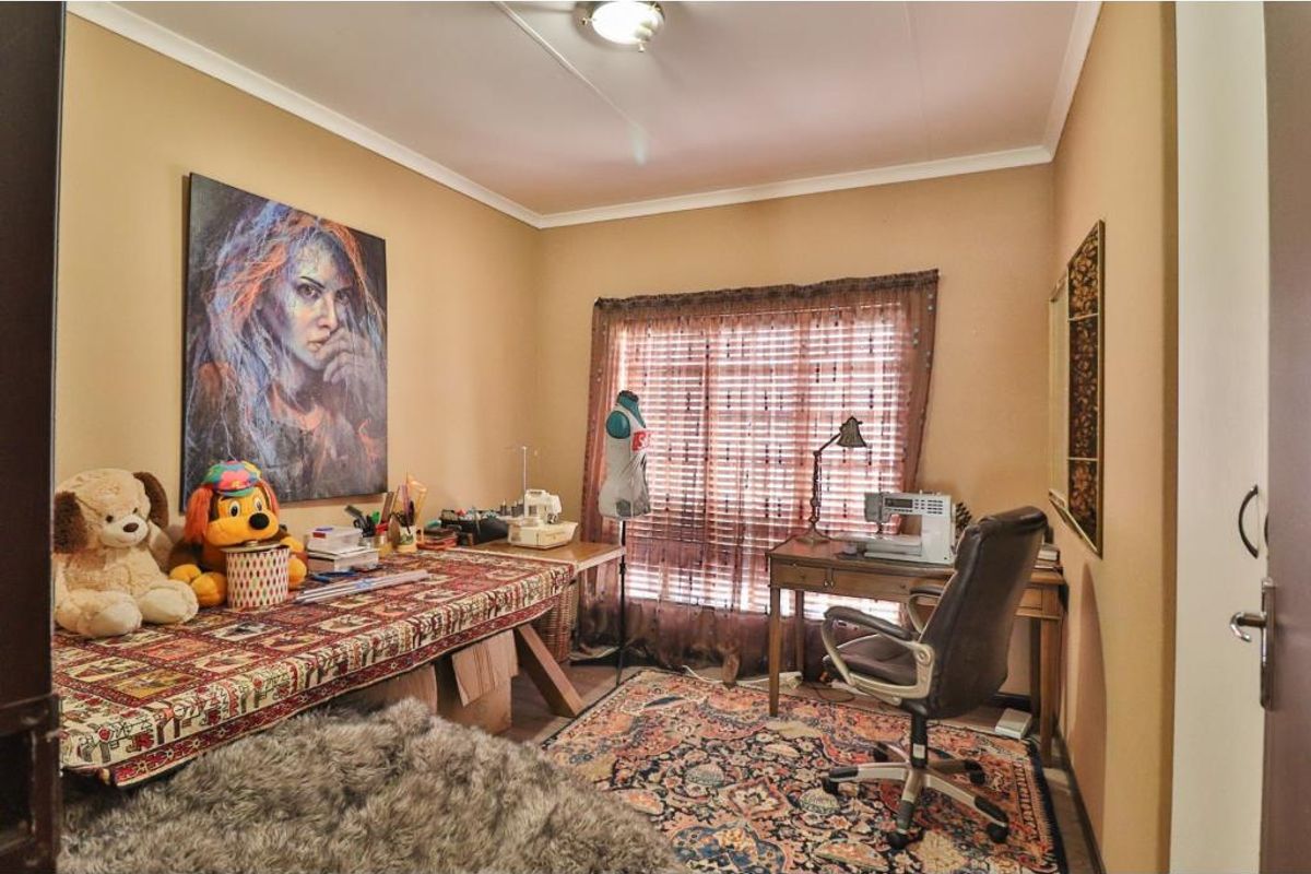 A functional bedroom currently utilized as a craft or hobby room, featuring neutral wall tones and a standard ceiling light fixture.