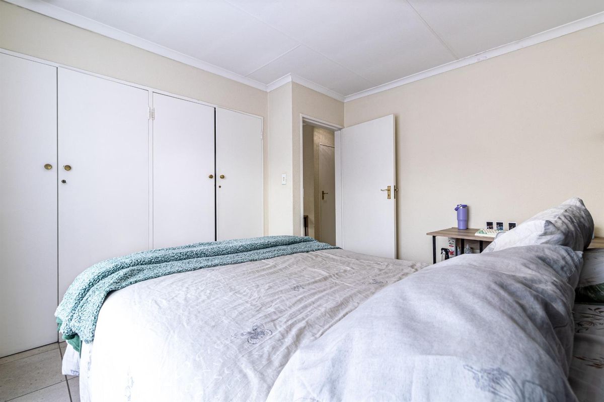 A functional bedroom featuring built-in cupboards, neutral wall finishes, and tiled flooring, providing a clean and practical living space.