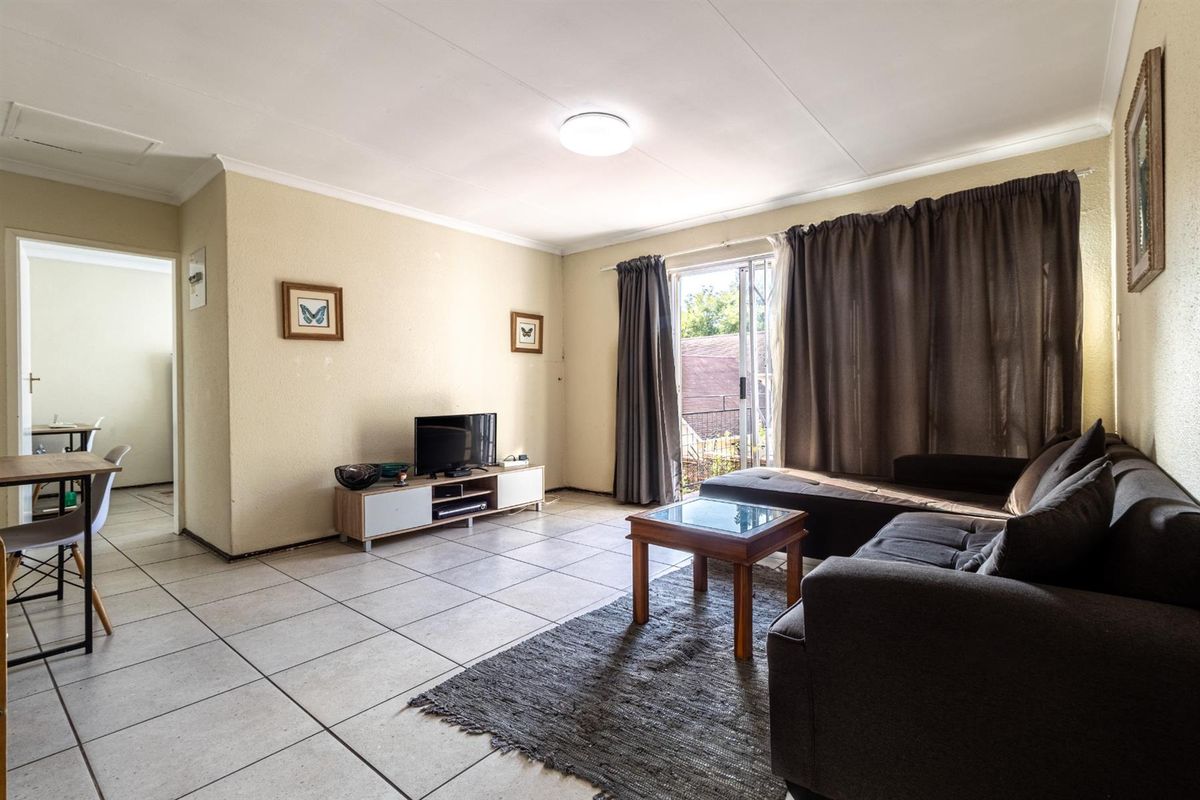 A living room featuring tiled flooring, a sliding glass door providing natural light, and neutral wall finishes.