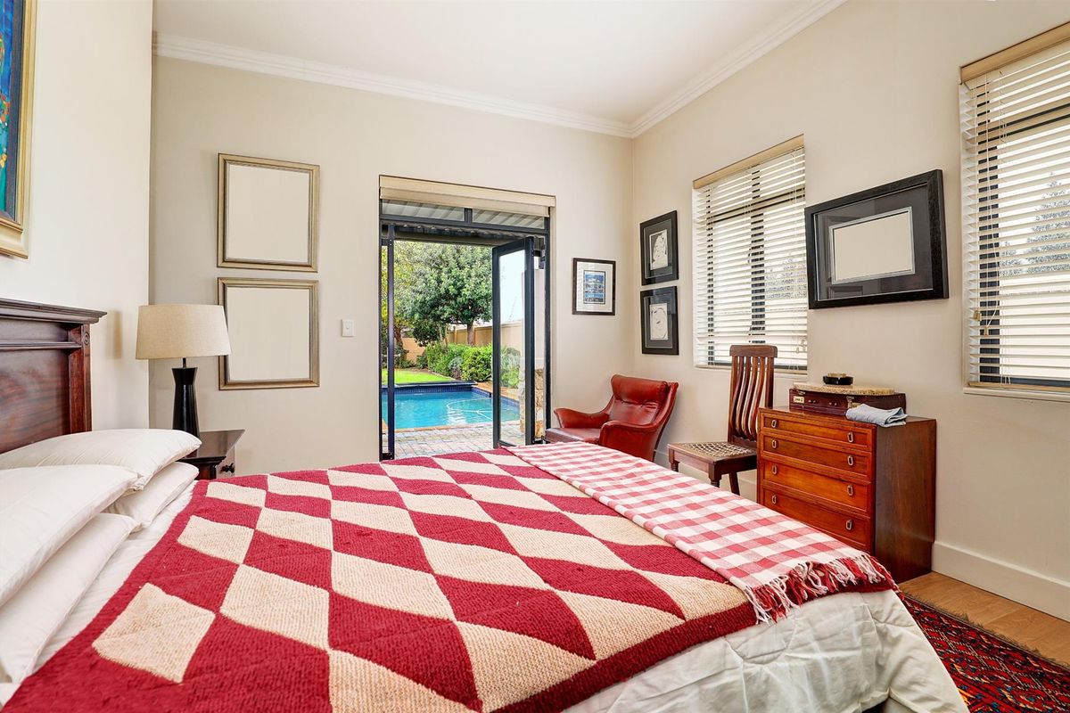 A well-maintained bedroom featuring direct access to a private outdoor pool area through glass-paneled doors, offering natural light and garden views.
