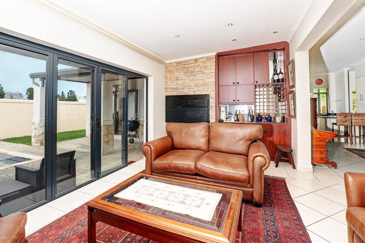 Living area featuring a built-in wooden bar unit, stone-clad fireplace, and large sliding glass doors providing seamless access to the outdoor patio and pool area.