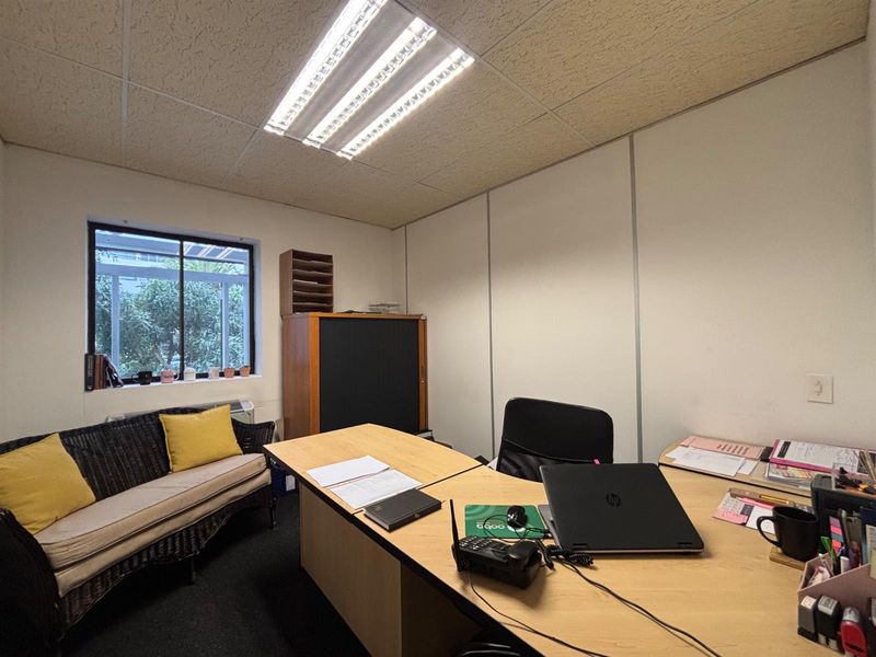 A functional office space featuring a suspended ceiling, fluorescent lighting, and carpet flooring, providing a practical environment for professional work.