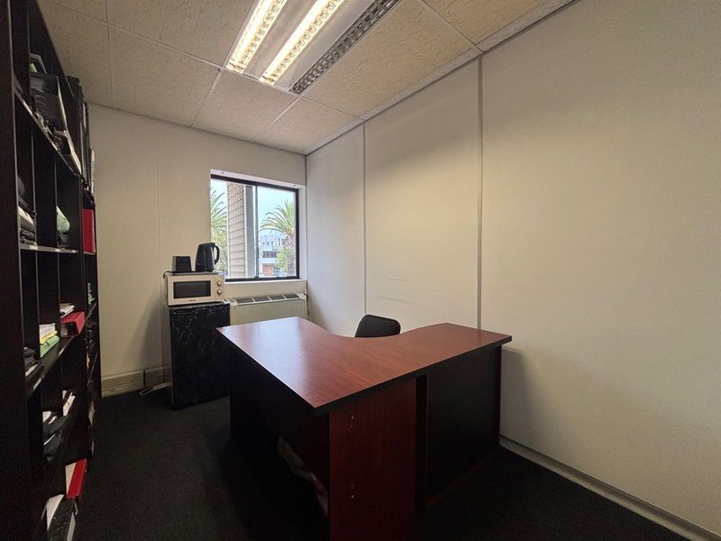 A functional office space featuring carpeted flooring, partition walls, and a suspended ceiling with integrated lighting.