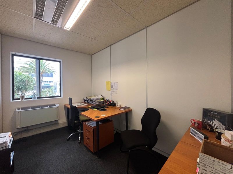 A functional office space featuring a suspended ceiling, recessed lighting, an integrated HVAC unit, and carpet flooring.