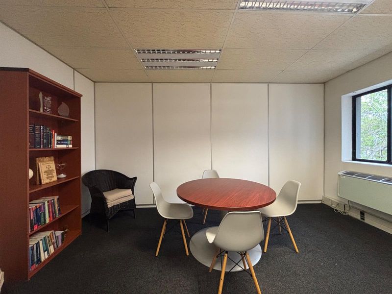 A functional office space featuring a suspended ceiling with recessed lighting, partition wall panels, and a window with an integrated HVAC unit.