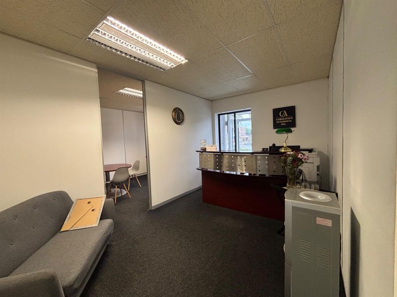 Office reception area featuring a built-in desk, drop ceiling with integrated lighting, and carpeted flooring.