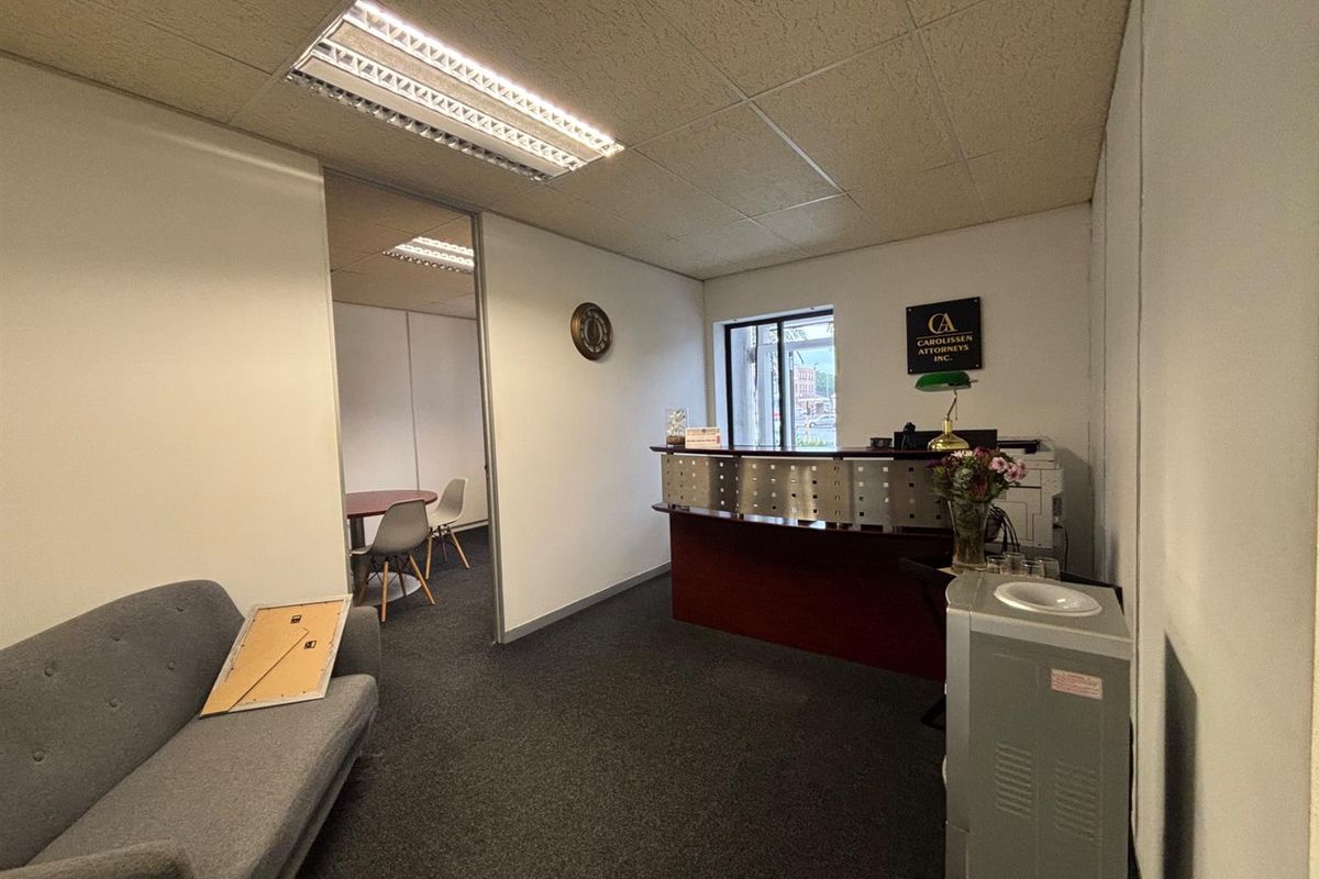 Office reception area featuring a built-in desk, drop ceiling with integrated lighting, and carpeted flooring.