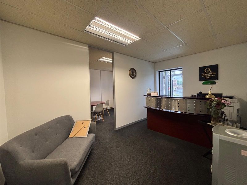 Professional office reception area featuring a built-in reception desk, carpeted flooring, and a suspended ceiling with integrated lighting.