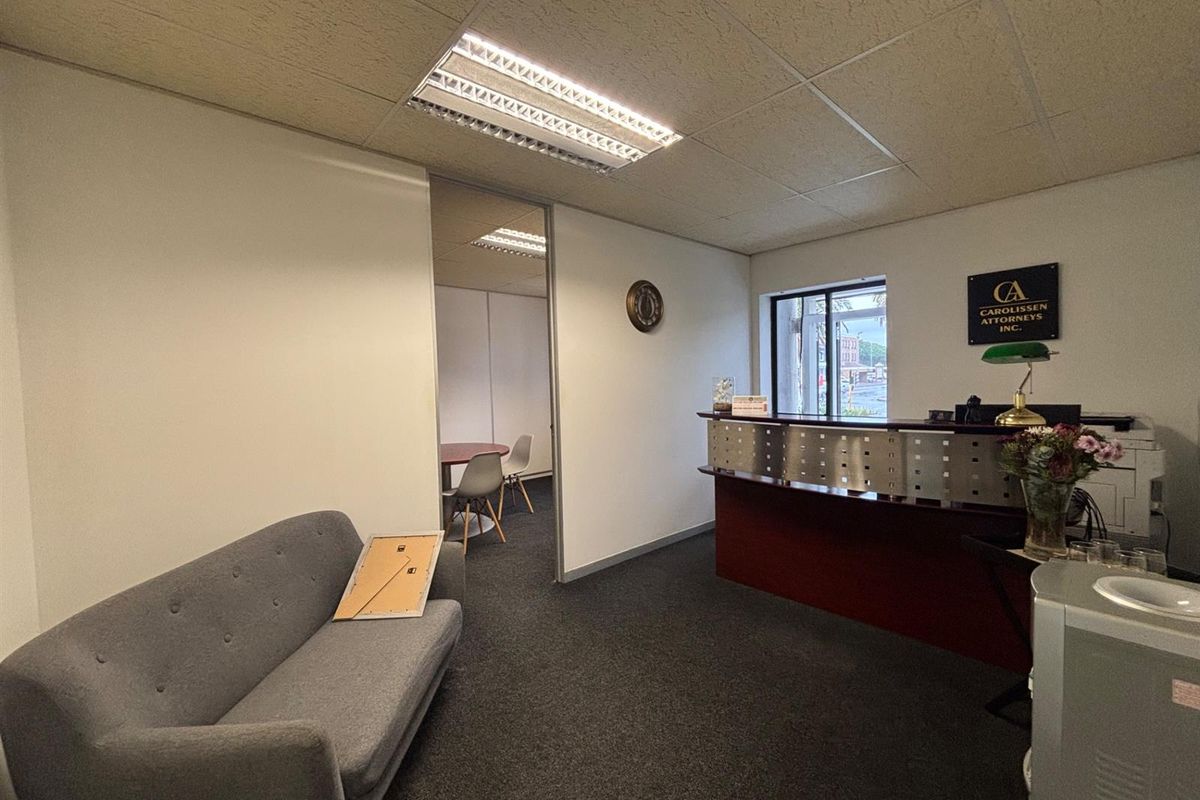 Professional office reception area featuring a built-in reception desk, carpeted flooring, and a suspended ceiling with integrated lighting.