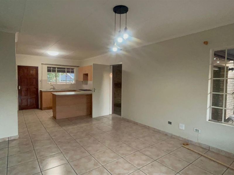 An open-plan living and kitchen area featuring tiled flooring, a breakfast counter, and built-in cabinetry, offering a functional and versatile living space.