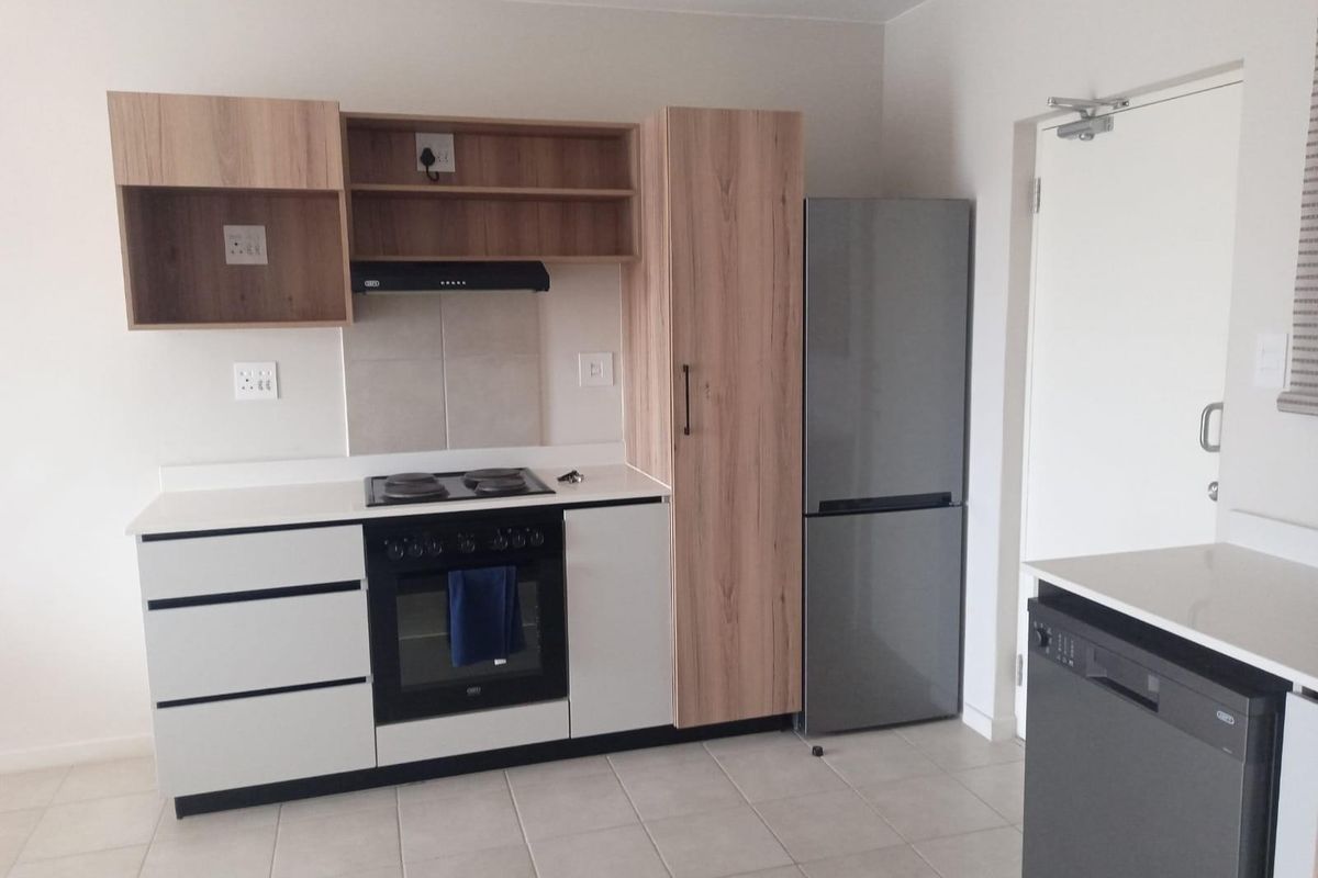 Modern kitchen featuring light wood-tone cabinetry, stone countertops, built-in oven and hob, and tiled flooring in a clean, functional layout.
