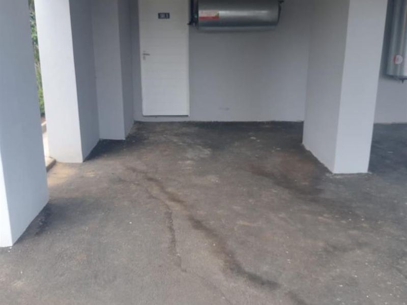A functional garage space featuring a concrete floor, exposed ceiling, and a wall-mounted electric geyser.