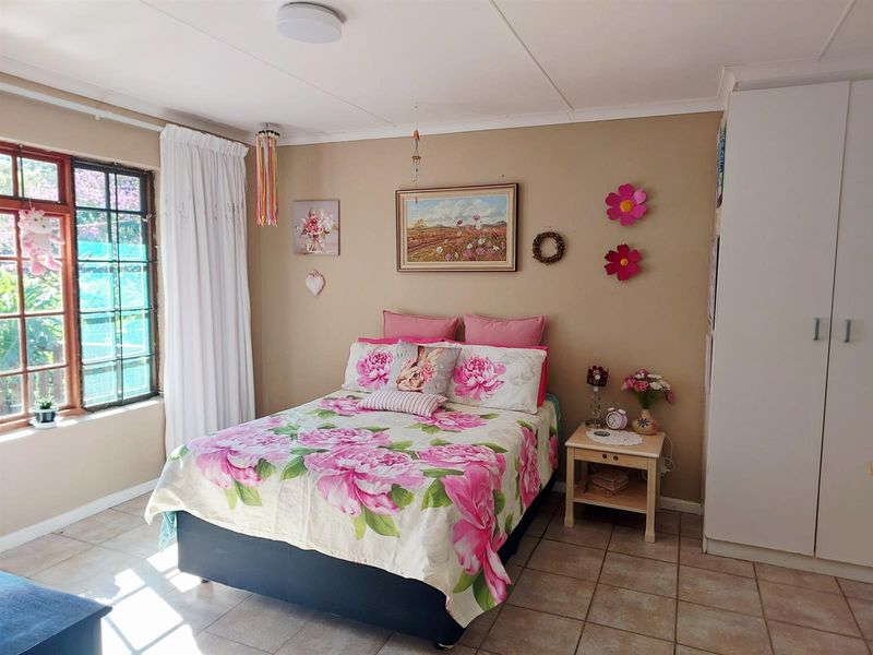A bedroom featuring tiled flooring, a built-in wardrobe, and a window with security bars, providing a functional and well-lit living space.