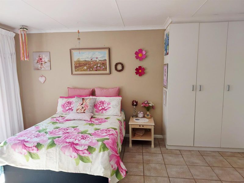 A bedroom featuring neutral wall paint, tiled flooring, and a white built-in wardrobe providing ample storage space.