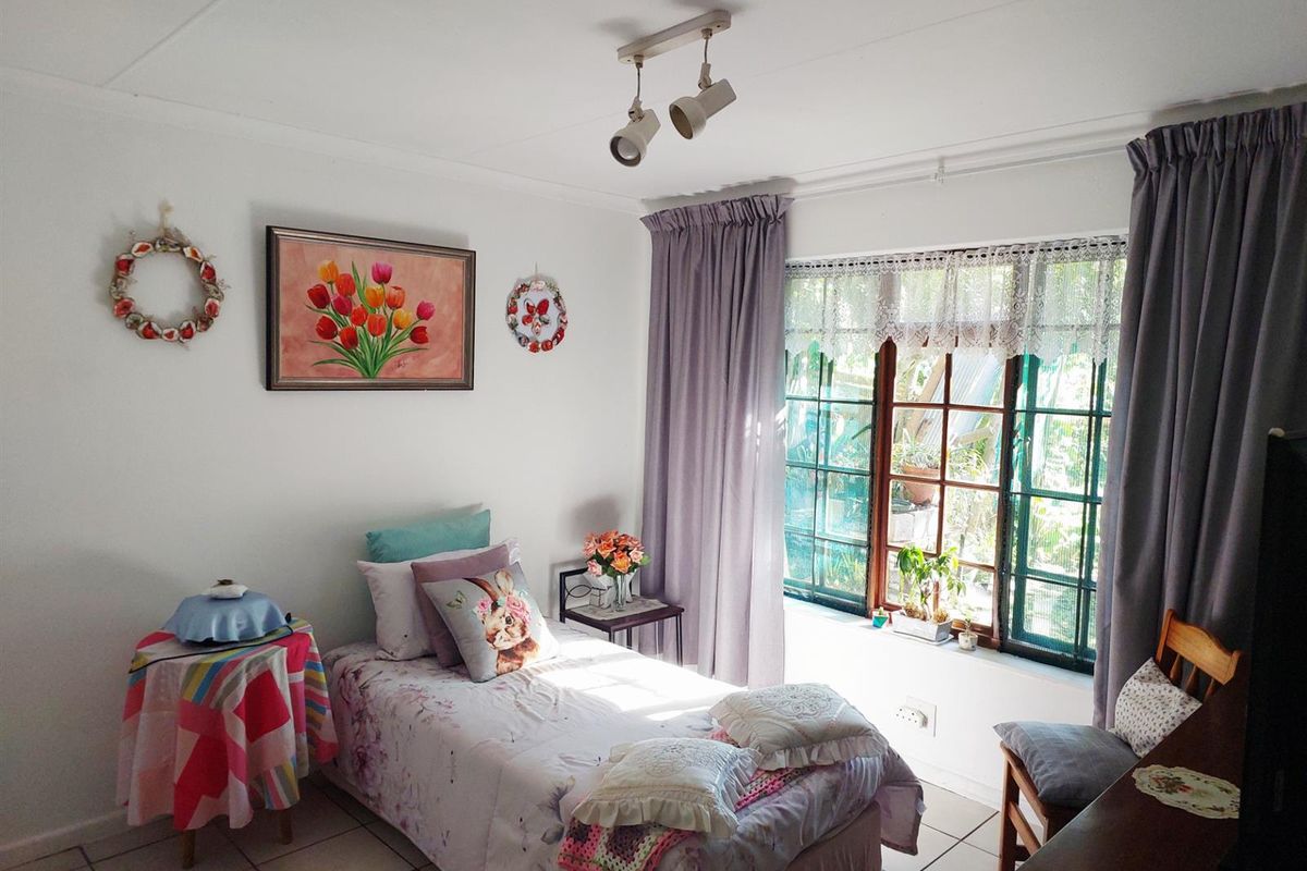 A cozy bedroom featuring tiled flooring, a multi-pane window with natural light, and adjustable track lighting.