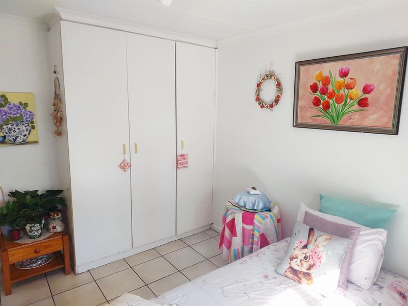 A bedroom featuring white built-in wardrobes and tiled flooring, offering a clean and functional space.