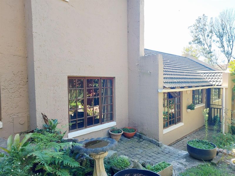 Rear exterior view of the property featuring a textured plaster facade, timber frame windows, and a paved patio area.