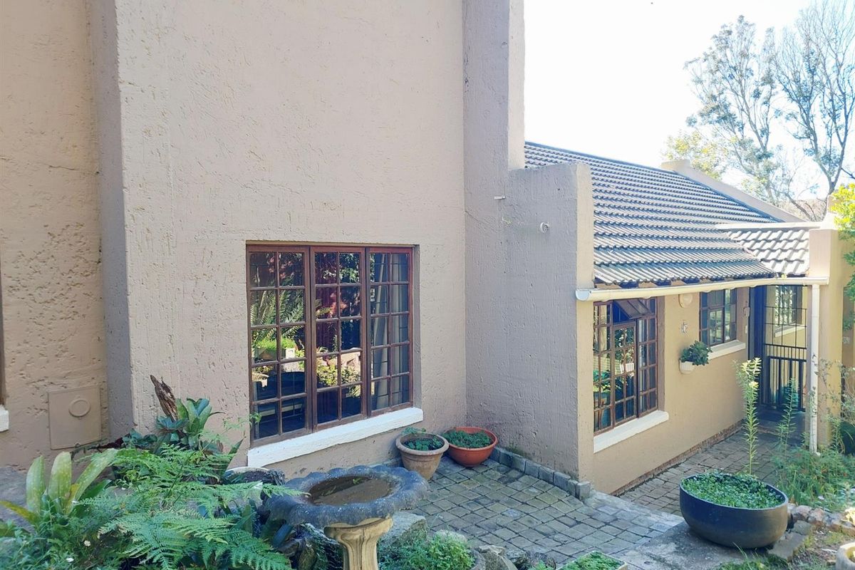 Rear exterior view of the property featuring a textured plaster facade, timber frame windows, and a paved patio area.