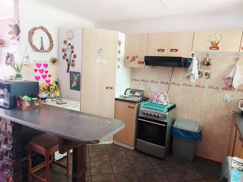 A functional kitchen featuring laminate cabinetry, a breakfast bar, tiled backsplash, and a freestanding stove with an extractor fan.