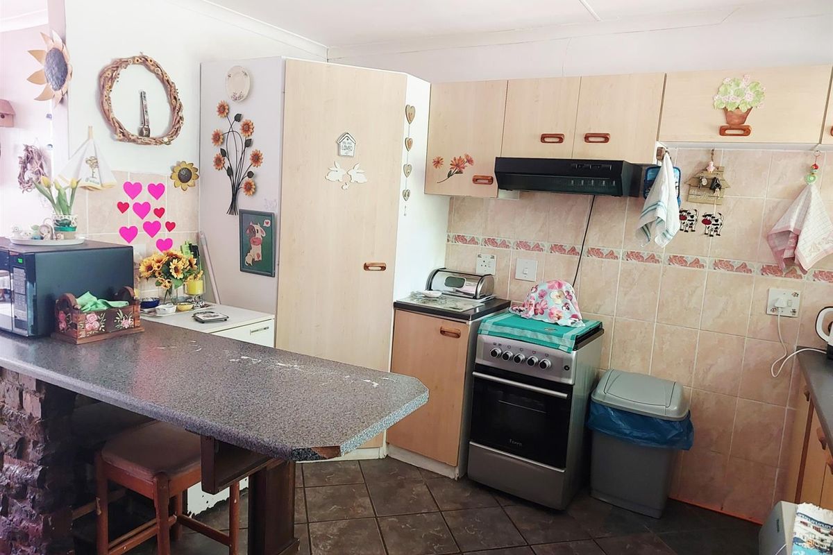 A functional kitchen featuring laminate cabinetry, a breakfast bar, tiled backsplash, and a freestanding stove with an extractor fan.