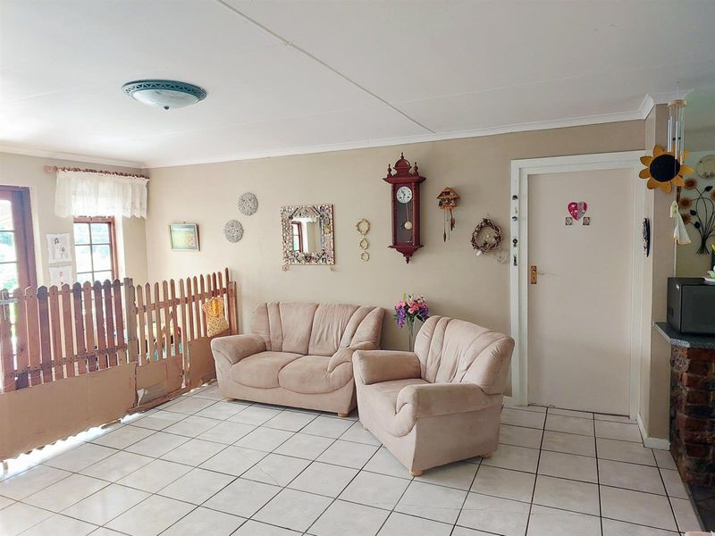 A living room area featuring tiled flooring, neutral wall finishes, and a standard internal door, requiring cosmetic updates to improve its overall appeal.