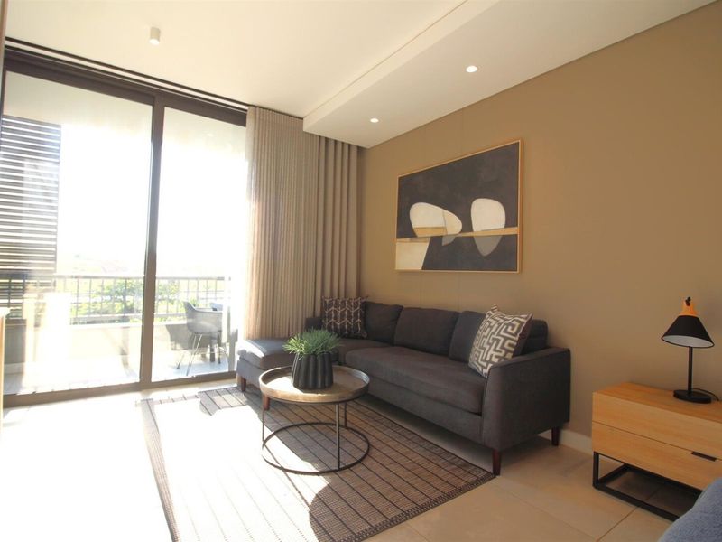 A modern, well-lit living room featuring large sliding glass doors that provide access to a private balcony and ample natural light.