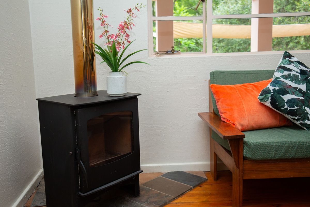 A cozy living area featuring a built-in wood-burning fireplace with a metal flue and timber flooring.