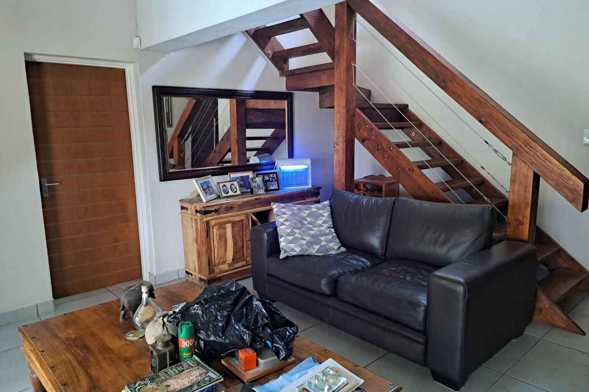 Living room area featuring a timber staircase with cable balustrades and tiled flooring.