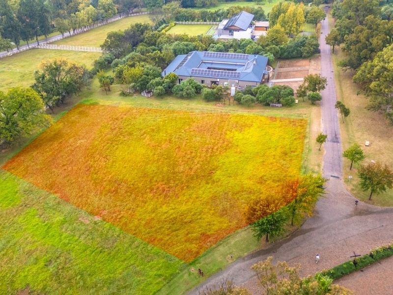 Aerial view of a vacant residential plot of land, highlighted in orange, situated within a landscaped estate setting.