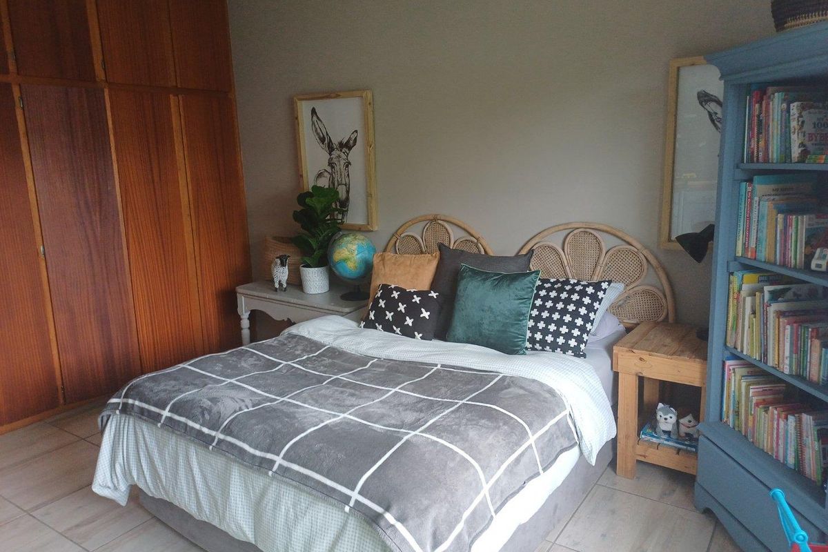 A cozy bedroom featuring built-in wooden cabinetry and tiled flooring, offering a functional and well-maintained living space.