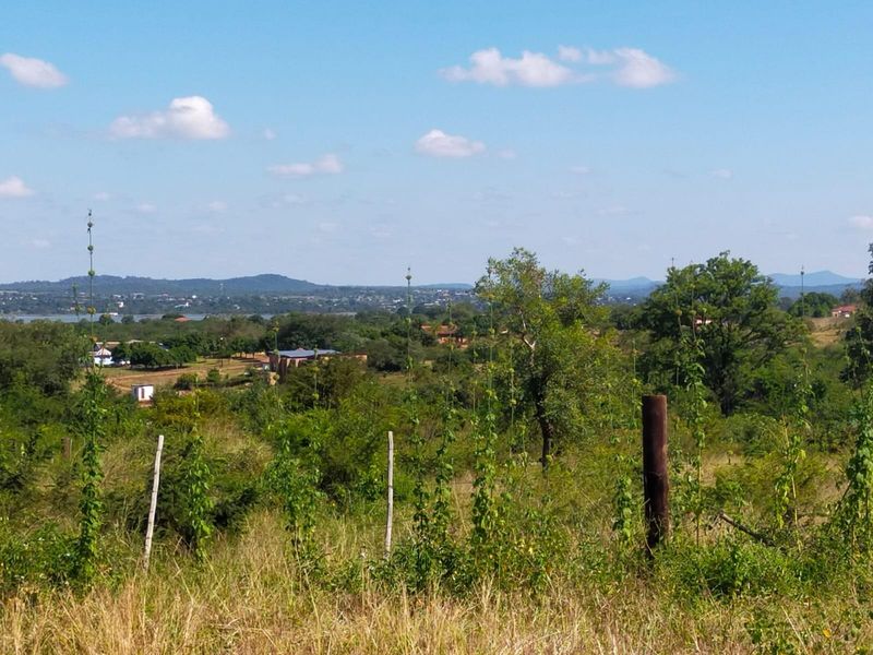 A scenic landscape view overlooking a rural area with natural vegetation and distant hills, captured from the vacant land property.