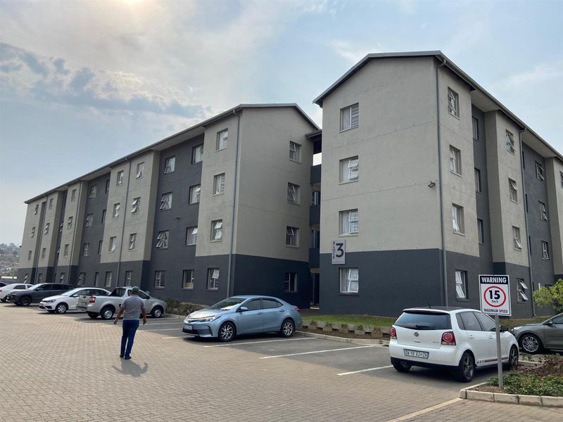 Exterior view of a multi-story apartment block featuring a paved parking area and modern facade finishes.
