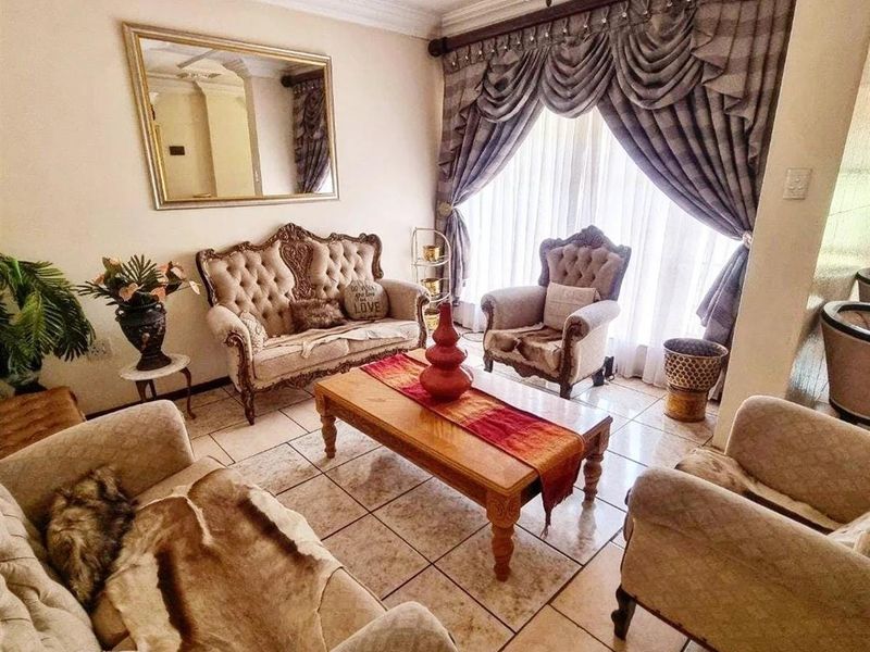 A formal living room featuring tiled flooring, decorative ceiling cornices, and a classic chandelier, offering a traditional aesthetic.