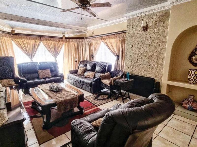 Spacious living room featuring a stone accent wall, built-in arched alcove, tiled flooring, and a decorative ceiling with a central fan.
