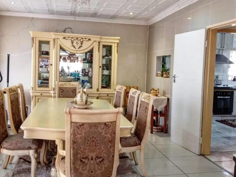 Dining room featuring tiled flooring, decorative ceiling tiles, and a crystal chandelier, with a view into the adjacent kitchen area.