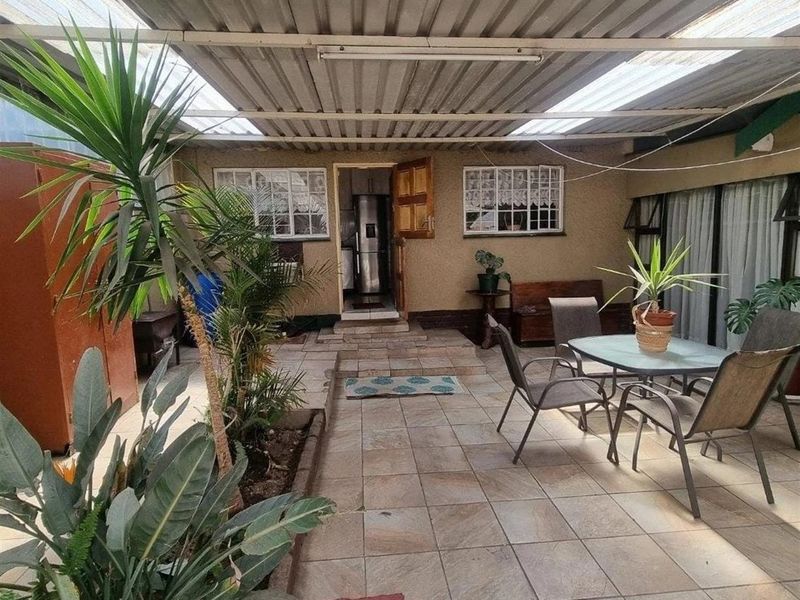 Covered outdoor patio area featuring tiled flooring, a corrugated roof with translucent panels, and direct access to the main house interior.