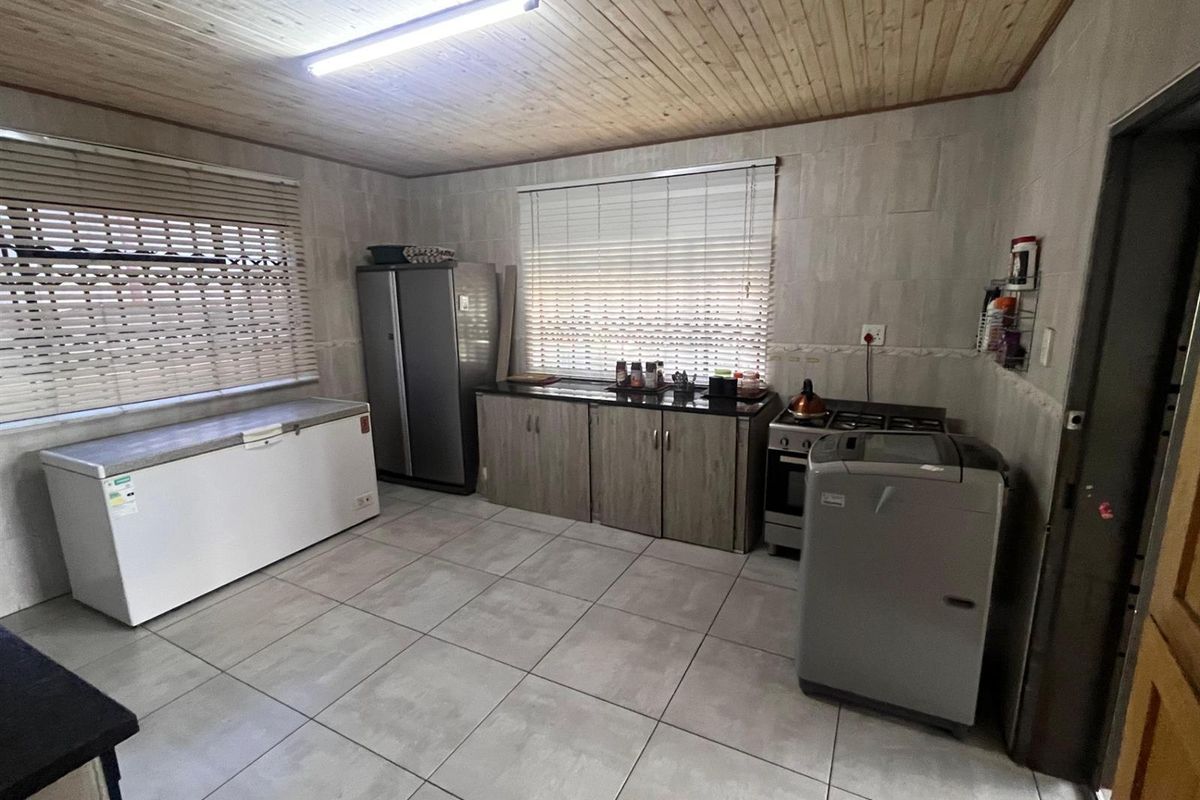 Functional kitchen and utility area featuring tiled flooring, built-in cabinetry, a gas stove, and a timber-paneled ceiling.