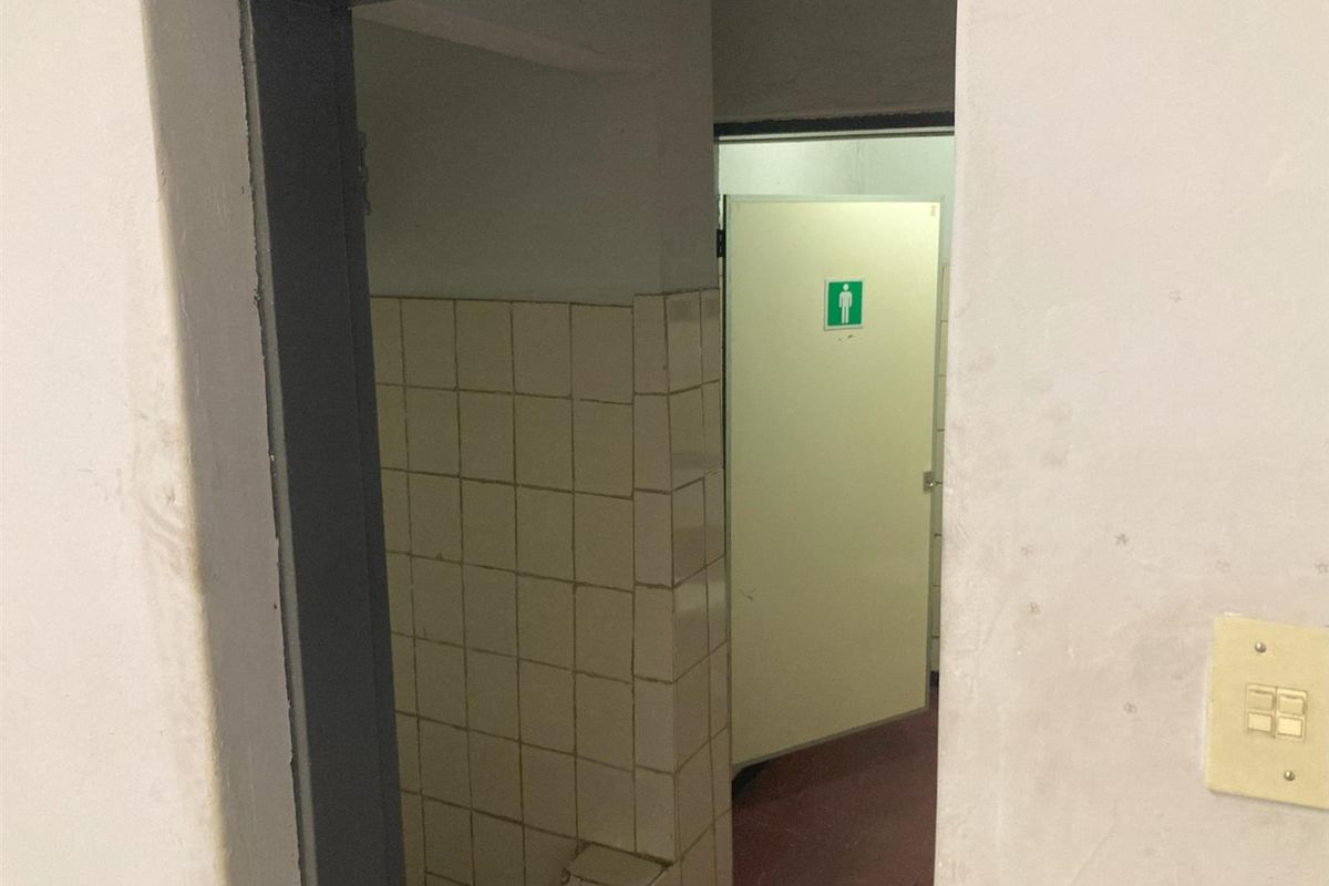 A view into a commercial restroom facility featuring tiled walls and a designated male entrance door.
