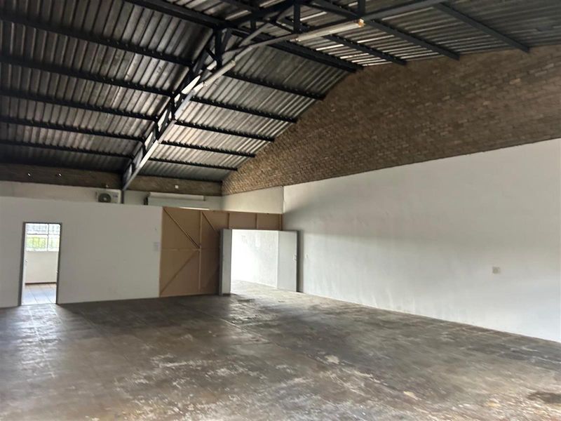 Spacious commercial warehouse or industrial unit featuring high vaulted ceilings, exposed brickwork, and durable concrete flooring, suitable for various business or storage applications.