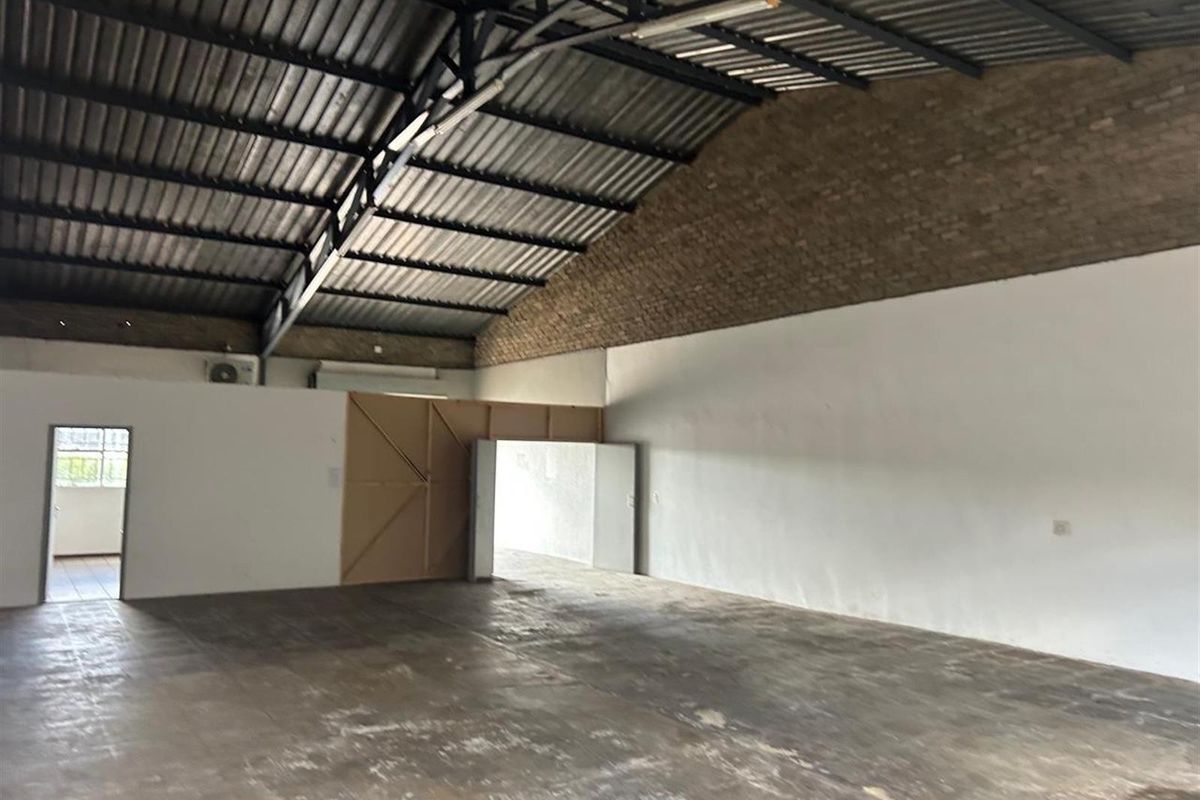 Spacious commercial warehouse or industrial unit featuring high vaulted ceilings, exposed brickwork, and durable concrete flooring, suitable for various business or storage applications.