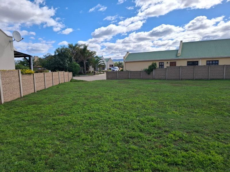 A vacant residential plot featuring established boundary walls and a level grassed surface, situated within a developed residential estate.