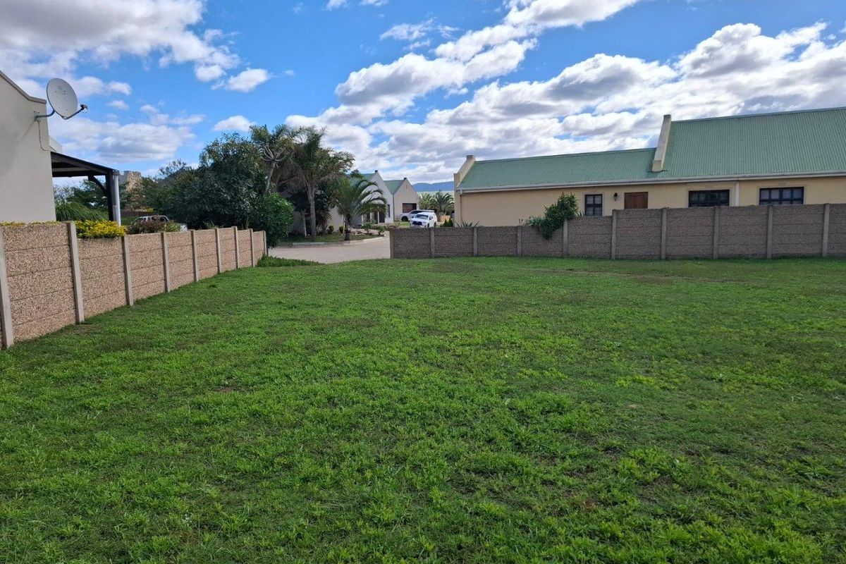 A vacant residential plot featuring established boundary walls and a level grassed surface, situated within a developed residential estate.