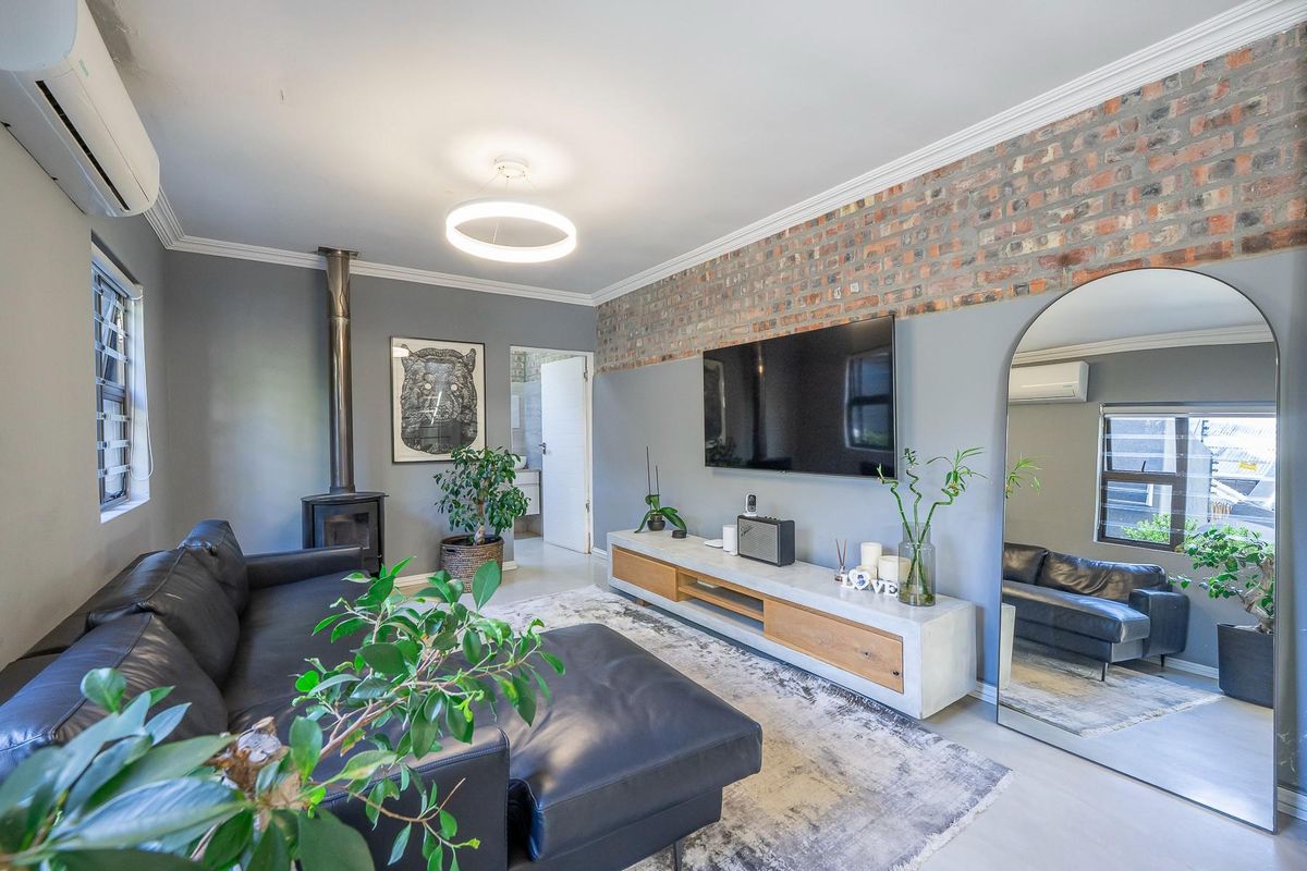 A modern living room featuring an exposed brick feature wall, a built-in wood-burning fireplace, and a wall-mounted air conditioning unit.
