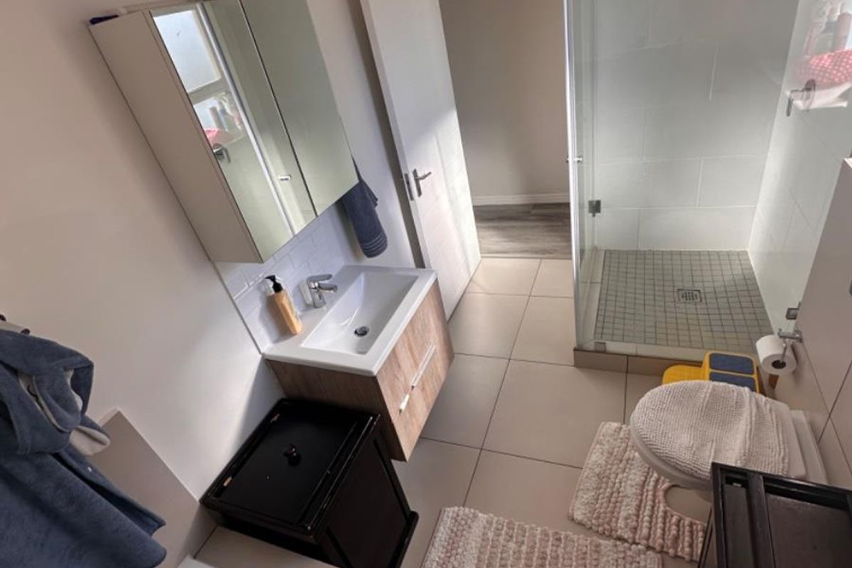 A modern bathroom featuring a glass-enclosed shower, a built-in bathtub, and a contemporary vanity unit with a mirrored cabinet.