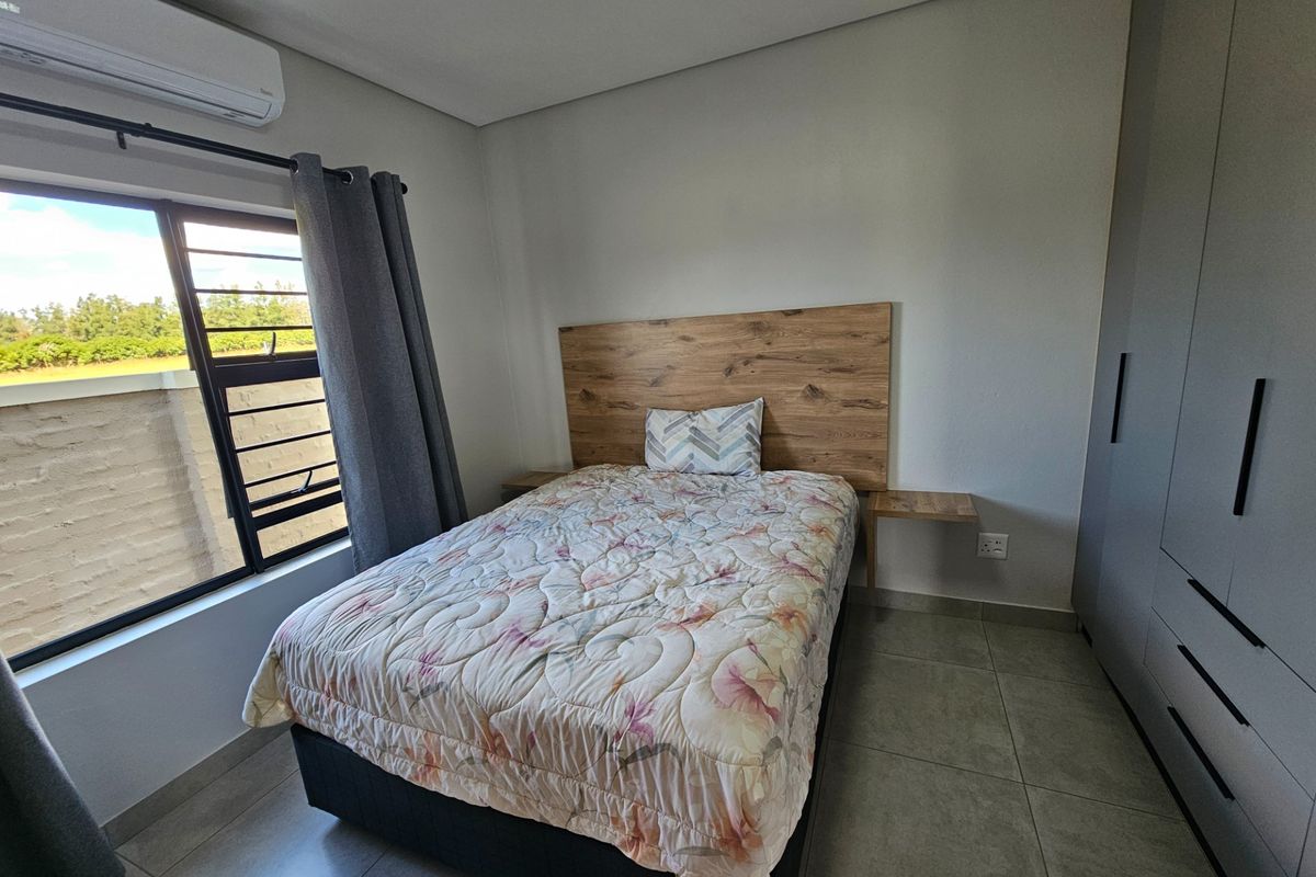 A well-maintained bedroom featuring built-in cupboards, a wall-mounted air conditioning unit, and tiled flooring.
