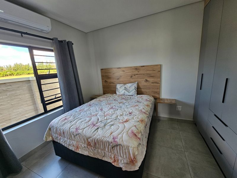 A well-maintained bedroom featuring built-in cupboards, a wall-mounted air conditioning unit, and tiled flooring.